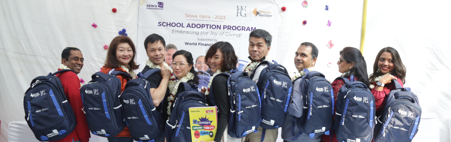 Volunteers and students holding new school backpacks at a School Adoption Programme event